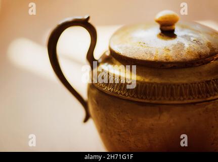 Die antike Kupfer elegante schöne Teekannen wird von einem hellen warmen Licht beleuchtet. Die magische Lampe von GENIE. Asiatischer alter Goldtopf. Stockfoto