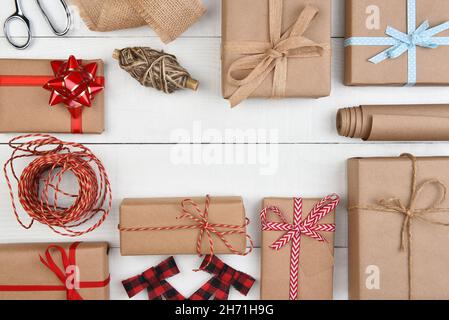 Christmas Flat Lay - Einfarbiges braunes Kraftpapier verpackt Geschenke und Accessoires mit mittlerer Kopiefläche. Stockfoto