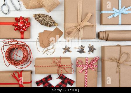 Christmas Flat Lay - Einfarbig braunes Kraftpapier verpackt Geschenke mit Zubehör füllen den gesamten Rahmen. Stockfoto