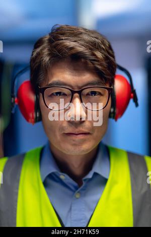 Porträt eines asiatischen Ingenieurs mit Ohrstöpseln im Computerserverraum Stockfoto