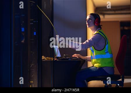 Kaukasische Ingenieurin berührt einen Draht im Computerserverraum Stockfoto