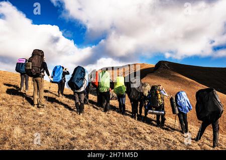 Gruppe von Reisenden mit großen Rucksäcken auf den Bergen. Rückansicht. Stockfoto