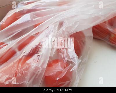 Schließen Sie rote Tomaten in einem Zellophanbeutel auf dem weißen Tisch. Stockfoto