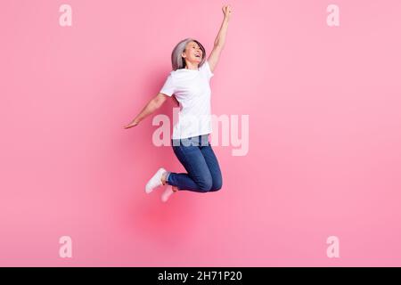 In voller Länge Körpergröße Ansicht von ziemlich glücklich fröhlich grauhaarige Frau springen jubelend isoliert über rosa Pastellfarbe Hintergrund Stockfoto