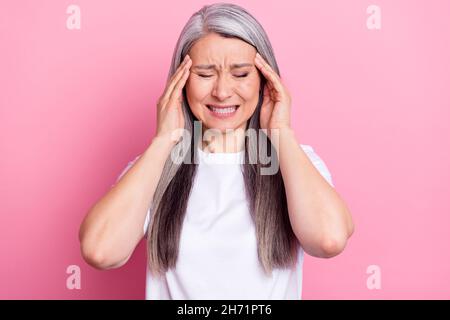 Foto-Porträt einer älteren Frau mit grauen Haaren leiden Kopfschmerzen isoliert auf pastellrosa Hintergrund Stockfoto