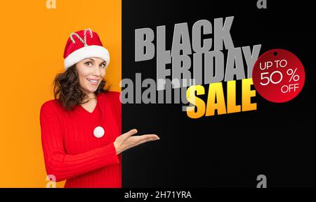 Black firday-Sonderangebot. Junges Mädchen in weihnachtsmann Hut auf hellen Hintergrund Farbe Geste Hand zu machen. Konzept für Neujahrs- und Weihnachtsfeiern. Frau in Stockfoto