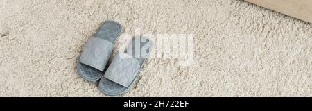 Blick auf graue Pantoffeln auf beigefarbenem Teppich, Banner Stockfoto