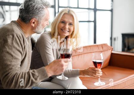 Harmonisches reifes Ehepaar mit Wein mit romantischen Datum, Ruhe nach dem Arbeitstag zu Hause, verbringen Zeit zusammen. Ehegatten mittleren Alters feiern wichtiges Datum, Jahrestag Stockfoto