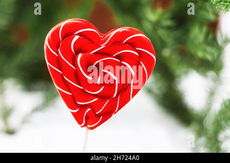 Lollipop-Süßigkeiten in Form eines rot-weißen Herzens isoliert auf einem unscharfen Bokeh-Hintergrund. Valentinstag-Konzept. Speicherplatz kopieren Stockfoto