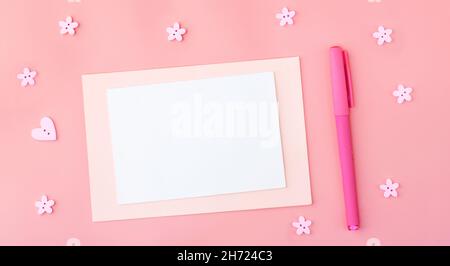 Farbige leere Blätter aus Pastellfarben auf einem rosa Hintergrund neben dem Stift, in der Nähe von romantischen Knöpfen in Form von Blumen und Herzen. Speicherplatz kopieren Stockfoto