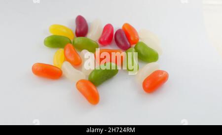 Verschiedene bunte Jelly-Bohnen liegen auf einer schlichten weißen Oberfläche Stockfoto