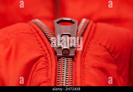 Nahaufnahme-Reißverschluss an hellroter Kleidung, Jacke. Reißverschluss mit Verschluss. Stockfoto