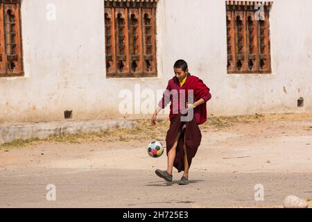 Ein junger buddhistischer Mönch übt seine Fußballkenntnisse an der Dechen Phodrang Klosterschule in Thimphu, Bhutan. Stockfoto
