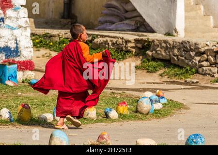 Ein junger buddhistischer Novizenmönch läuft an der Dechen Phodrang Klosterschule in Thimphu, Bhutan, um sich in eine Schlange zu stellen. Stockfoto