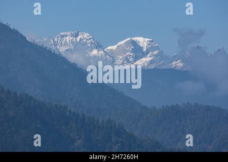 Schneebedeckte Gipfel im Himalaya durch die Wolken am Dochu La Pass in Bhutan. Stockfoto