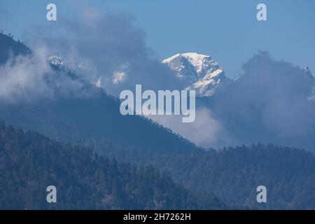 Schneebedeckte Gipfel im Himalaya durch die Wolken am Dochu La Pass in Bhutan. Stockfoto