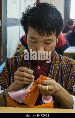 Ein Nähstudent am National Institute of the Thirteen Arts lernt Stickereien und Seidenapplikationen in Thimphu, Bhutan. Stockfoto