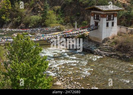 Gebetsfahnen säumen die letzte verbliebene eiserne Kettenbrücke in Bhutan über den Paro Chhu Fluss in der Nähe von Paro, Bhutan. Stockfoto