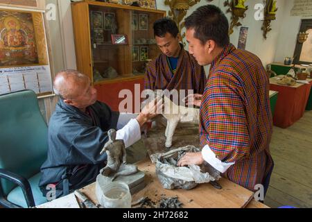 Ein Kunstlehrer unterstützt zwei Studenten bei einem Keramikprojekt im National Institute for the Thirteen Arts in Thimphu, Bhutan. Stockfoto