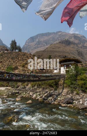 Gebetsfahnen säumen die letzte verbliebene eiserne Kettenbrücke in Bhutan über den Paro Chhu Fluss in der Nähe von Paro, Bhutan. Stockfoto