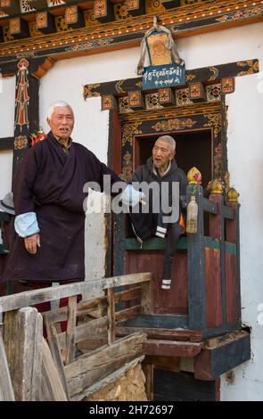 Zwei ältere bhutanische Männer in der Tür eines Bauernhauses am Tamchhog Lhakhang Tempel in der Nähe von Paro, Bhutan. Stockfoto