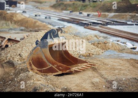 Bau der Eisenbahnstrecke. Baggerschaufel auf der Baustelle der neuen Straßenbahnverbindung. Stockfoto