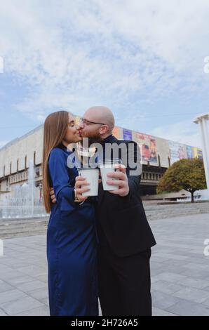 Glückliche Familie, ein Paar, das in der Stadt Kaffee trinkt. Urbane Liebesgeschichte eines stylischen jungen Geschäftsmanns in einem blauen Anzug mit rotem Bart. Und attraktive Frau Stockfoto