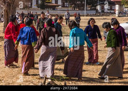 Eine Gruppe bhutanesischer Frauen tanzen in einem Bogenschießwettbewerb in Paro, Bhutan, für das Siegerteam der Männer. Stockfoto