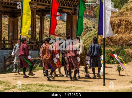 Ein bhutanesisches Bogenschießteam tanzt bei einem Bogenschießwettbewerb in Thimphu, Bhutan, einen traditionellen Siegesfest-Tanz. Stockfoto