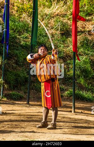 Ein bhutanesischer Bogenschütze konkurriert bei einem Bogenschießwettbewerb in Thimphu, Bhutan, mit einem rekurvten Bogen. Stockfoto