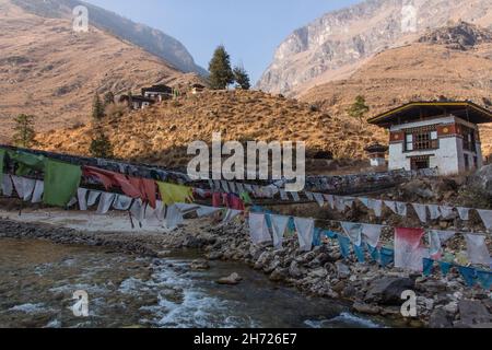 Gebetsfahnen säumen die eiserne Kettenbrücke über den Paro Chhu River in der Nähe des Tamchhog Lhakhang Tempels in Bhutan. Stockfoto