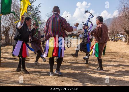 Ein bhutanesisches Bogenschießteam tanzt bei einem Bogenschießwettbewerb in Paro, Bhutan, einen traditionellen Siegesfest-Tanz. Stockfoto