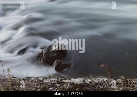 Langzeitaufnahme von einzelnen, untergetauchten Steinen, die im Fluss liegen Stockfoto