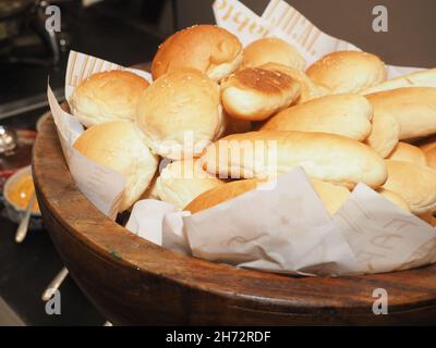 Nahaufnahme von frisch gebackenen Brötchen auf einer Holzschüssel mit Zutaten im Hintergrund Conc Stockfoto