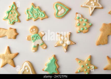 Auswahl an weihnachtlich geformten Plätzchen mit weißer und grüner Vereisung auf weißem Tisch. Draufsicht. Horizontale Zusammensetzung. Stockfoto