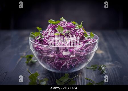 Lila Kohl. Rotkohl- und Petersiliensalat, auf dunklem Holzhintergrund Stockfoto