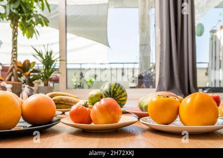 Rosafarbene Tomaten, reife Kaki, Grapefruits und Mangos zwischen den Gängen Stockfoto