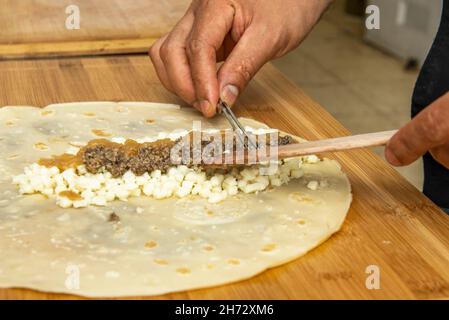 Die Hände des Küchenchefs bereiten eine herzhafte Crepe-Füllung zu Stockfoto