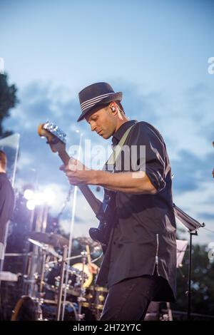 Männlicher Gitarrist, der unter blauem Himmel E-Gitarre spielt Stockfoto