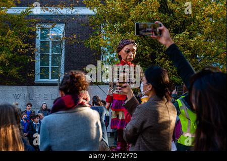 Den Haag, Niederlande. 19th. November 2021. Am letzten Tag ihres Besuchs in den Niederlanden spazierte die riesige Marionette „Little Amal“, ein neun Jahre altes Mädchen aus Syrien, das über 11 Meter groß ist, durch das Stadtzentrum von Den Haag, wo sich das Repräsentantenhaus befindet, Mit den Menschen auf der Straße zu interagieren. Dieser Besuch wurde von Amare organisiert, einem neuen kulturellen Zentrum im Rahmen des Open Festivals. Mit ihrem Besuch will Amal in ganz Europa die Aufmerksamkeit auf die Not junger Flüchtlinge lenken, die aus Syrien geflohen sind. Während h Stockfoto