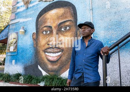 Der Künstler Marvin Weeks posiert vor seinem Wandgemälde von Ahmaud Arbery, dem schwarzen Jogger, der von weißen Bewohnern getötet wurde, das auf der Seite des Brunswick African American Cultural Center am 18. November 2021 in Brunswick, Georgia, gemalt wurde. Stockfoto