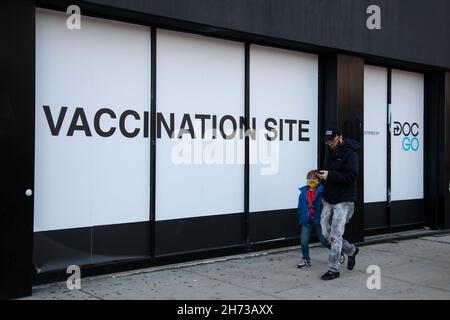 New York, USA. 19th. November 2021. Fußgänger gehen am 19. November 2021 vor einer COVID-19-Impfstelle im Stadtteil Brooklyn in New York, USA. Die US-amerikanische Food and Drug Administration (FDA) hat am Freitag Booster der Pfizer/BioNTech- und Moderna COVID-19-Impfstoffe für alle Erwachsenen zugelassen. Quelle: Michael Nagle/Xinhua/Alamy Live News Stockfoto