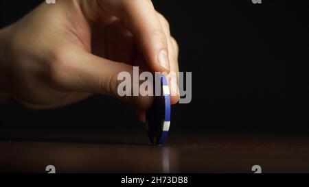 Poker Chip dreht sich auf dem Tisch. Casino-Thema. Pokerspiel, Pokerchips auf dem Tisch, auf schwarzem Hintergrund. Stockfoto