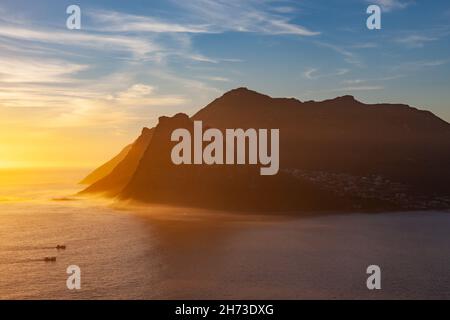 Fischerboote, die bei Sonnenuntergang in die Hout Bay in der Nähe von Kapstadt in Südafrika fahren. Vom Chapman's Peak aus gesehen. Stockfoto