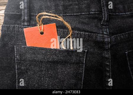 Roter Anhänger in der Gesäßtasche der schwarzen Jeans. Verkäufe am Black Friday Stockfoto