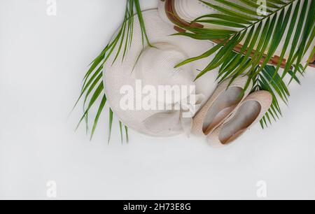 Reiseset in weißen Farben. hut, Schuhe, Koffer unter Palmblättern auf weißem Hintergrund. Reisen Stockfoto