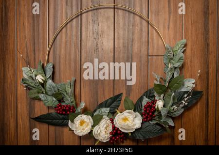 Moderner Weihnachtskranz auf Holzhintergrund mit Blumen Stockfoto