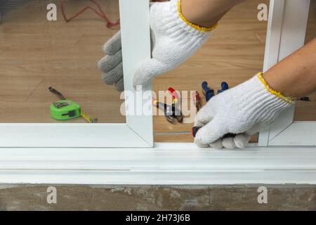 Arbeiter, der die Schiebetür des Insektenschutzschirms fixiert Stockfoto