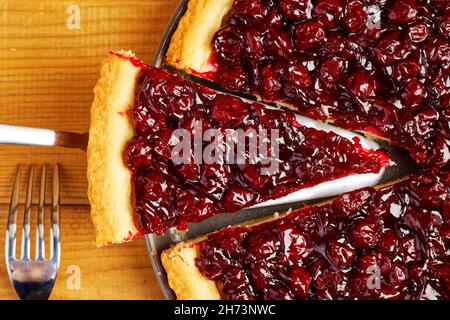 Nahaufnahme hausgemachter Beerenkuchen mit Kirsche auf Holztisch. Draufsicht. Stockfoto