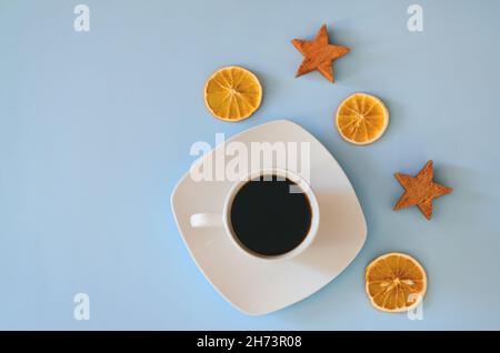 Weihnachten, Neujahr flach lag auf blauem Hintergrund. Weihnachtliche Dekoration mit trockenen Gewürzen, Orangenringen, Zimt. Tasse heißen schwarzen Kaffee. Notizbuch Papier Stockfoto